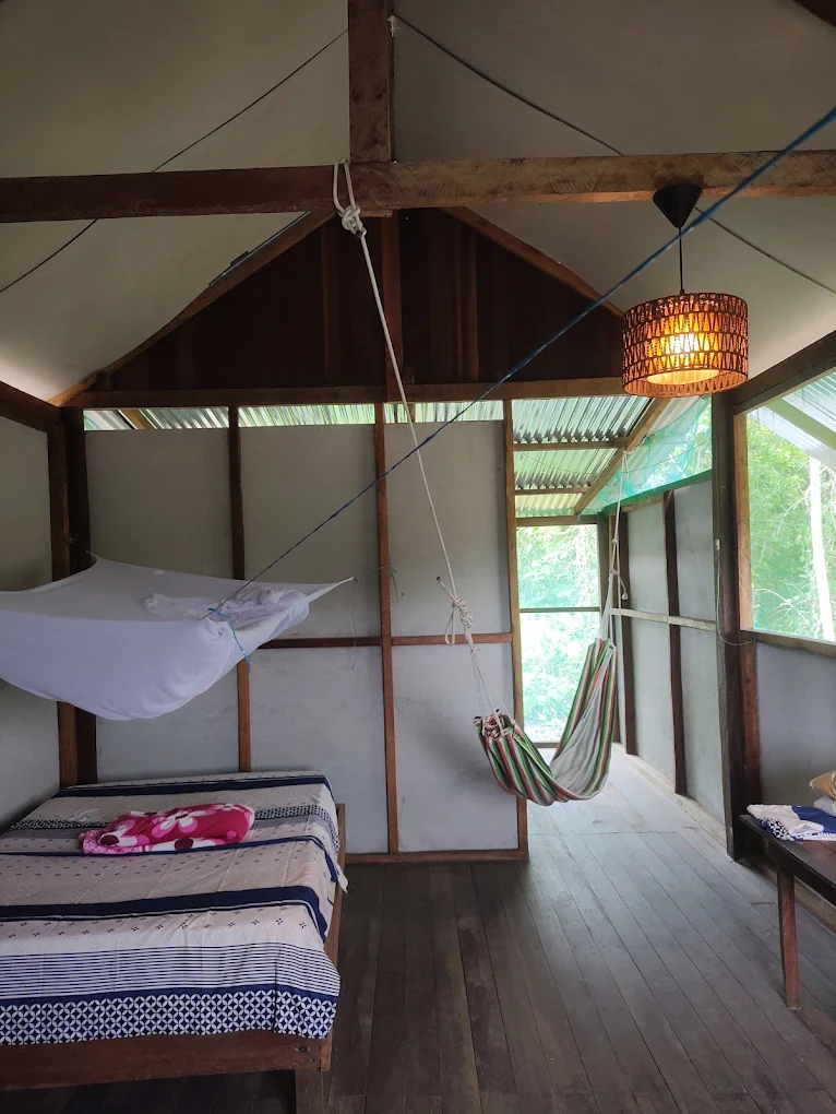 Sacred Private Retreat room with a bed, mosquito net, hammock and wooden floor