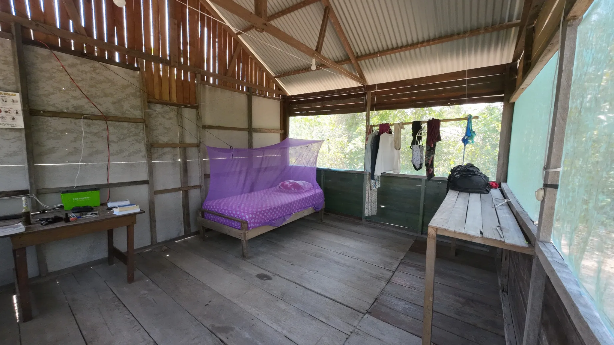 An actual retreat bedroom with a purple mosquito net and wooden walls