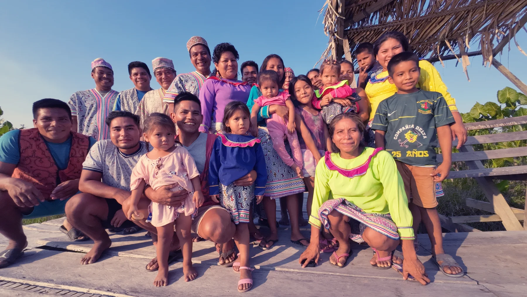 Adults and children gathered on a wooden platform in the community